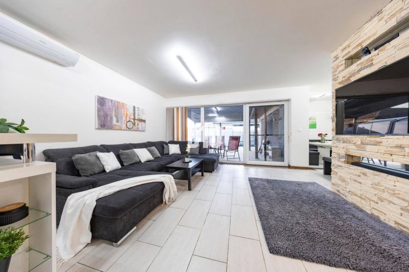 Wohnzimmer eines Einfamilienhauses mit Sofa, Kamin und Schiebetüren zur Terrasse.