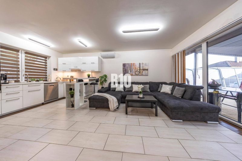 Helles Wohnzimmer in einem Einfamilienhaus mit Küche und großem Sofa.