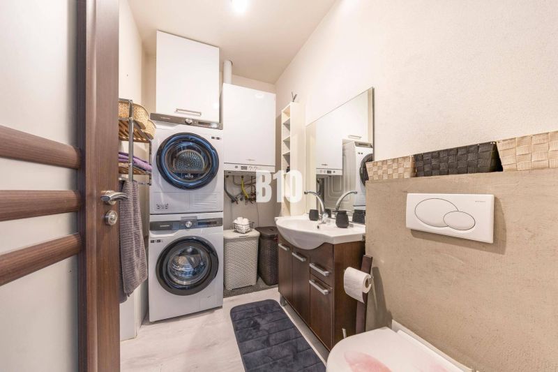 Badezimmer in einem Einfamilienhaus mit Waschmaschine, Trockner, Waschbecken und Stauraum.