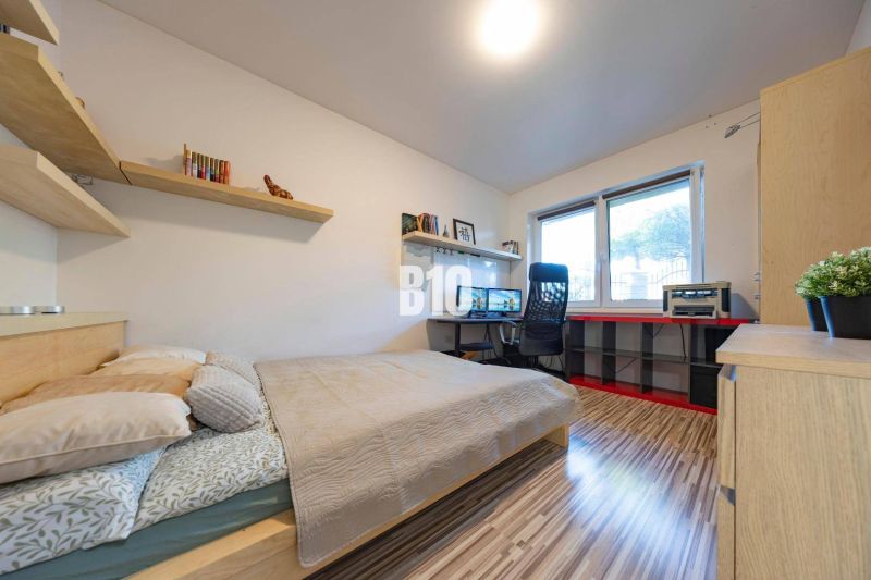 Schlafzimmer im Einfamilienhaus mit Schreibtisch, Regalen und Holzboden.