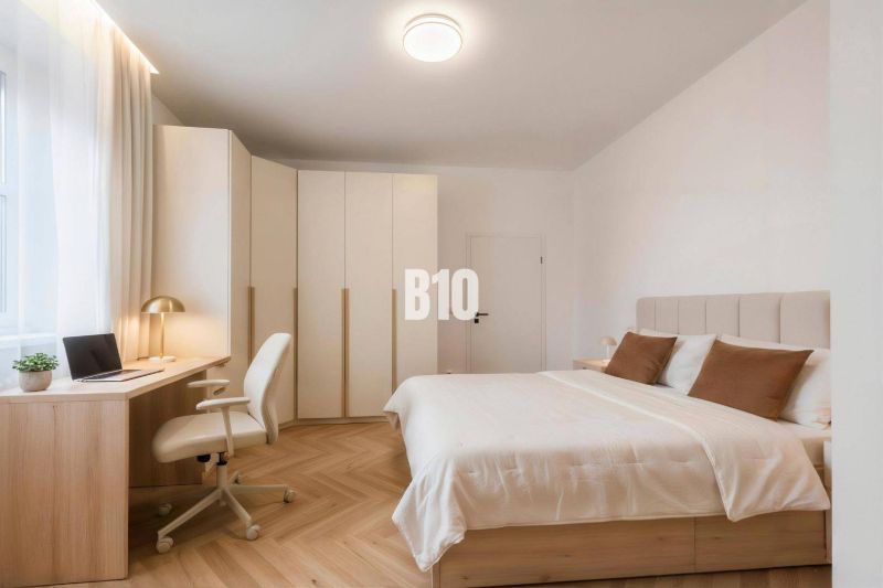 Schlafzimmer in einer 4-Zimmer-Wohnung mit Holzboden, Schreibtisch und Einbauschrank.