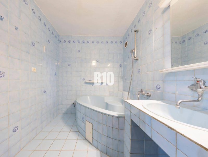 Ein Badezimmer mit hellblauen Fliesen, einer Badewanne und einem Waschbecken in einer 4-Zimmer-Wohnung.