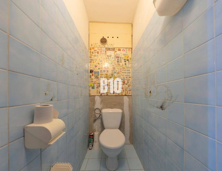Badezimmer in einer 4-Zimmer-Wohnung mit blauen Fliesen und Toilette.