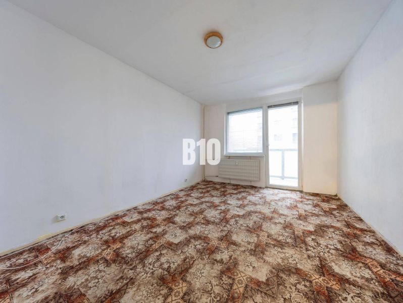 Wohnzimmer in einer 4-Zimmer-Wohnung mit Teppichboden und großem Fenster.