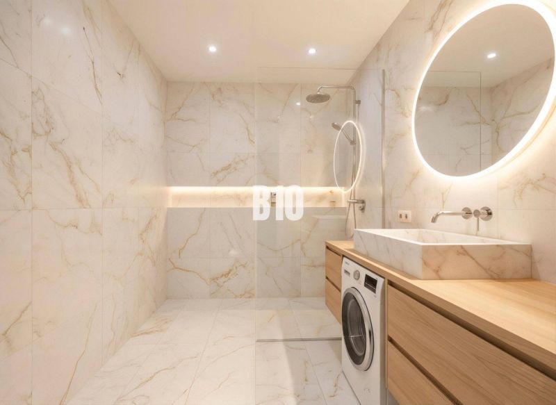 Badezimmer in einer 4-Zimmer-Wohnung mit großer Dusche, Waschmaschine und beleuchtetem Spiegel.