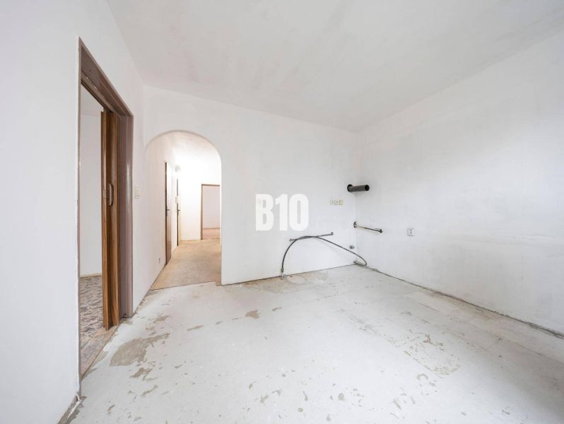 Neingerichtetes Zimmer in einer 4-Zimmer-Wohnung mit weißen Wänden und Betonboden.