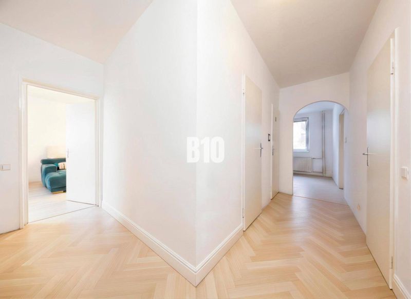 Der Flur in der 4-Zimmer-Wohnung mit einem Boden in Holzoptik und hellen Wänden.