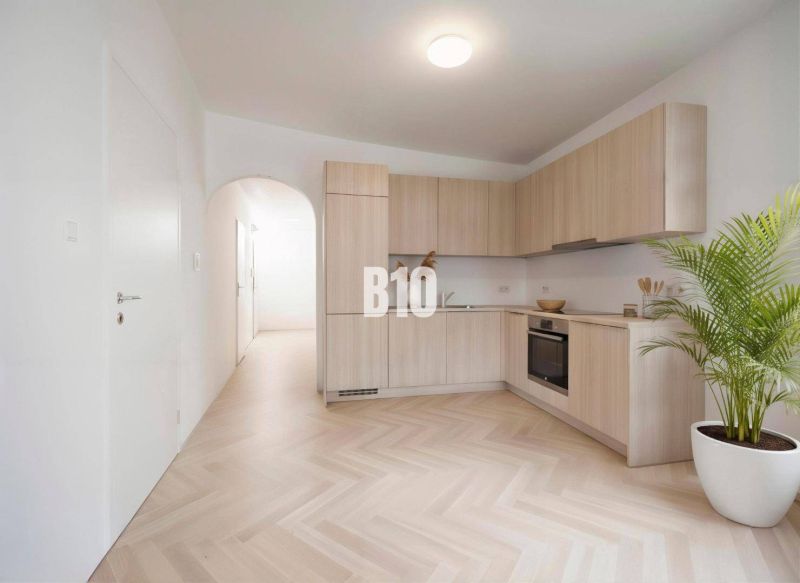 Küche in einer 4-Zimmer-Wohnung mit Holzboden und hellen Möbeln.