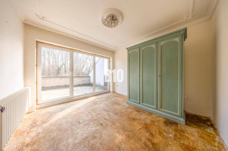 Ein Interieur eines Zimmers in einem Einfamilienhaus mit einem großen grünen Kleiderschrank und Glastüren.