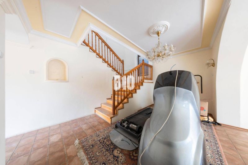 Interieur eines Einfamilienhauses mit Treppe, Kronleuchter, Boden und Sportgerät.