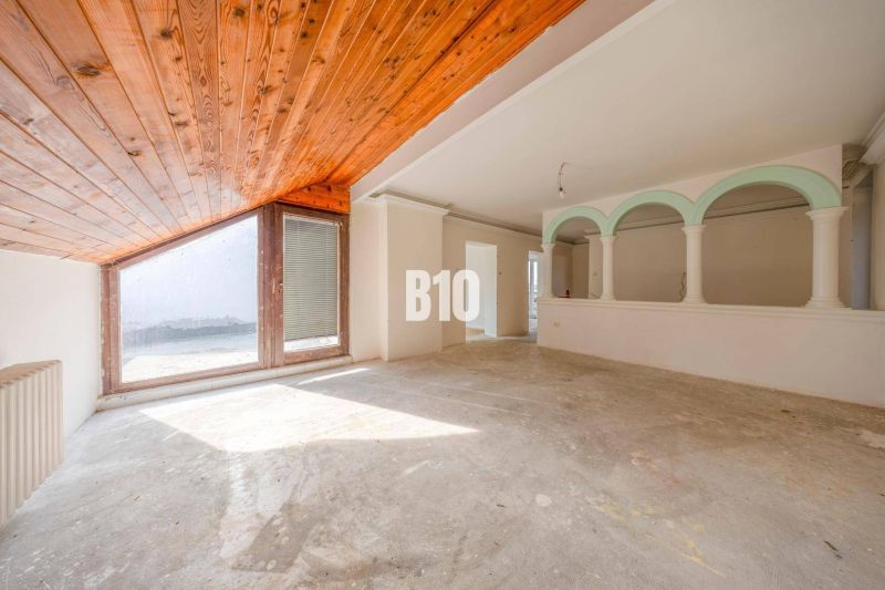 Geräumiges Interieur eines Einfamilienhauses mit großem Fenster und Holzbalkendecke.