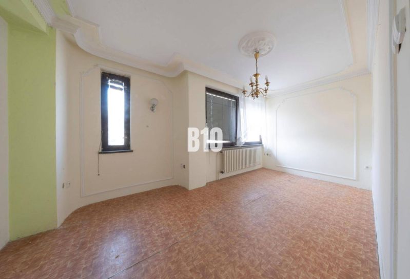 Wohnzimmer in einem Einfamilienhaus mit Kronleuchter und Boden in Holzoptik.