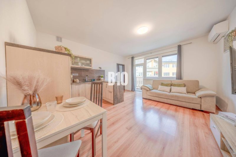 Innenraum einer 2-Zimmer-Wohnung mit Holzboden, Sofa und Esstisch.