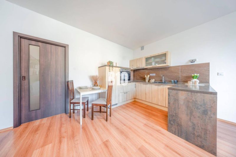 Küchenecke in einer 2-Zimmer-Wohnung mit Holzboden und Esstisch.
