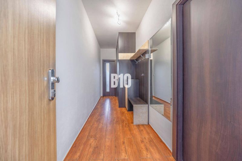 Ein schmaler Flur mit einem Spiegel und einem Boden in Holzoptik in einer 2-Zimmer-Wohnung.