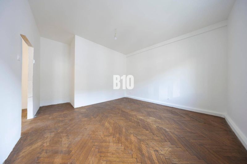 Ein geräumiges Zimmer mit weißen Wänden und einem Boden in Holzoptik in einer 3-Zimmer-Wohnung.