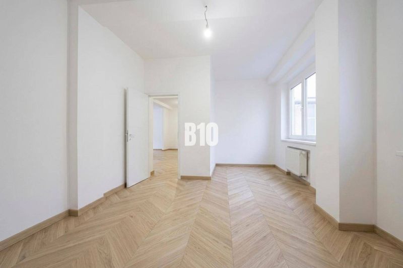 Ein Zimmer mit weißen Wänden und einem Boden in Holzoptik in einer 3-Zimmer-Wohnung.