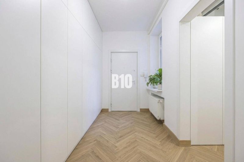 Ein gemütlicher Flur mit weißen Wänden, einem Boden in Holzoptik und einer Pflanze in einer 3-Zimmer-Wohnung.