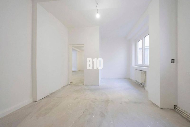 Interieur einer leeren 3-Zimmer-Wohnung mit weißen Wänden und einem großen Fenster.