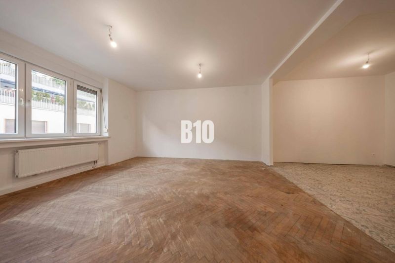 Wohnzimmer in einer 3-Zimmer-Wohnung mit Holzboden und großen Fenstern.