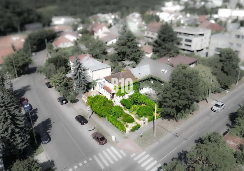 Ein Einfamilienhaus in der Gegend von Bratislava - Altstadt, umgeben von Grünflächen und einer Straße mit Autos.