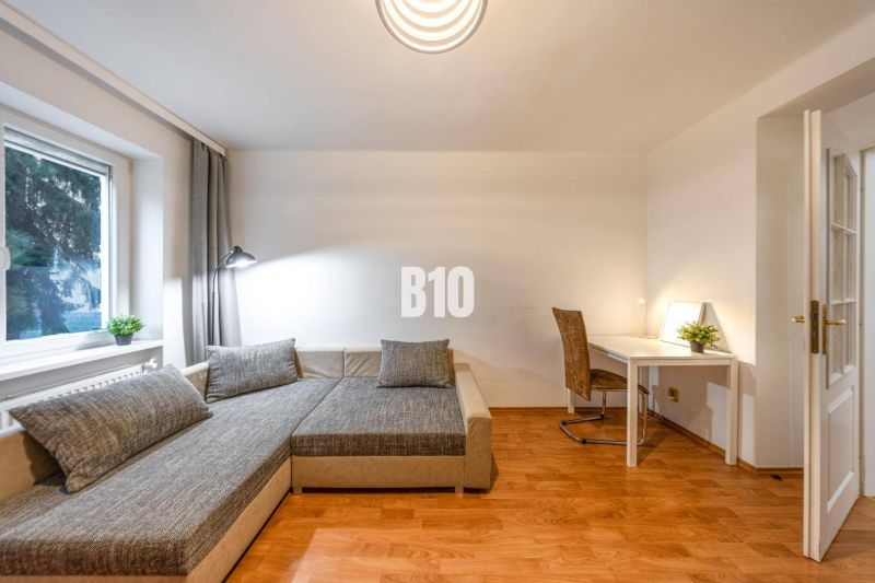 Wohnzimmer in einer 2-Zimmer-Wohnung mit Sofa, Tisch und Holzboden.