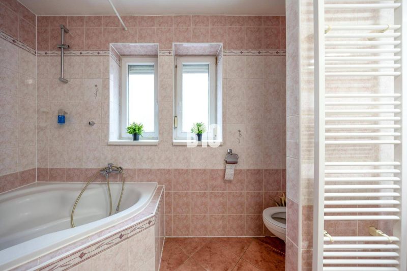 Badezimmer mit Badewanne, zwei Fenstern und Heizkörper in einer 2-Zimmer-Wohnung.