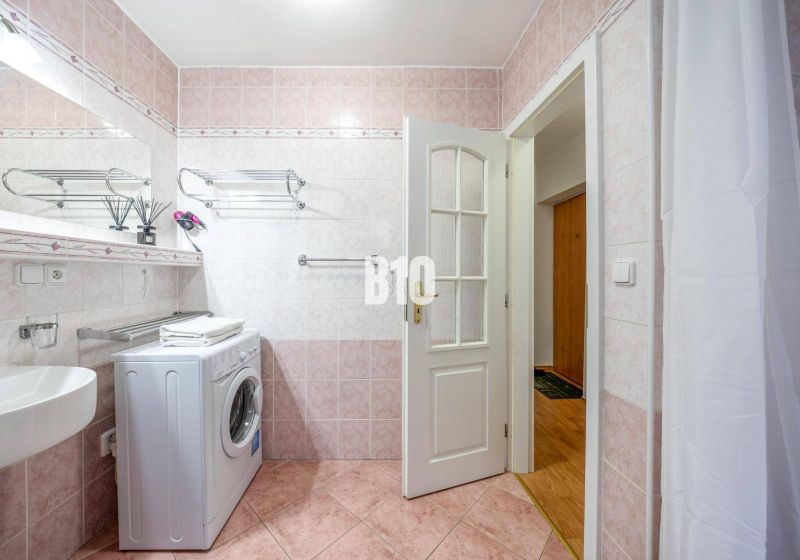 Badezimmer mit Waschmaschine und rosa Fliesen in einer 2-Zimmer-Wohnung.
