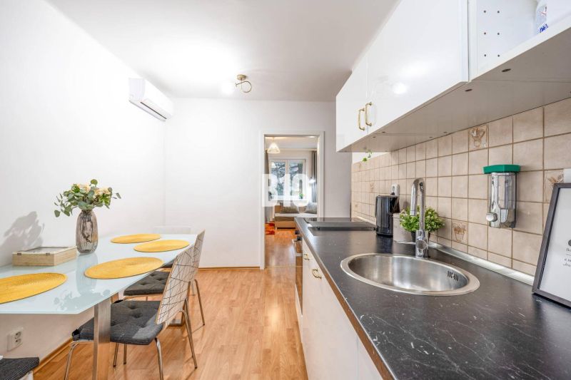 Küche mit Tisch, Stühlen und Boden in Holzoptik in einer 2-Zimmer-Wohnung.
