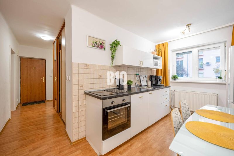 Küche in einer 2-Zimmer-Wohnung mit eingebauten Geräten und einem Bodenbelag in Holzoptik.