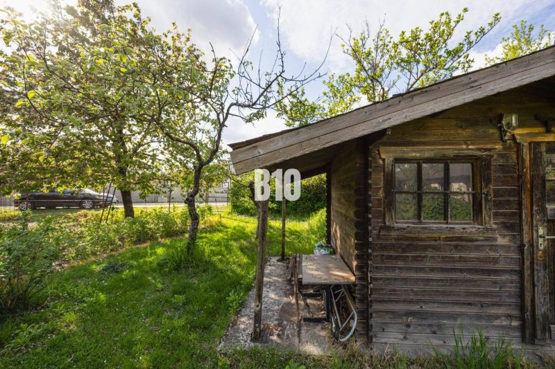 Ein Garten mit einer Holzhütte, umgeben von Bäumen auf einem Grundstück in Dunajská Lužná zum Wohnen.