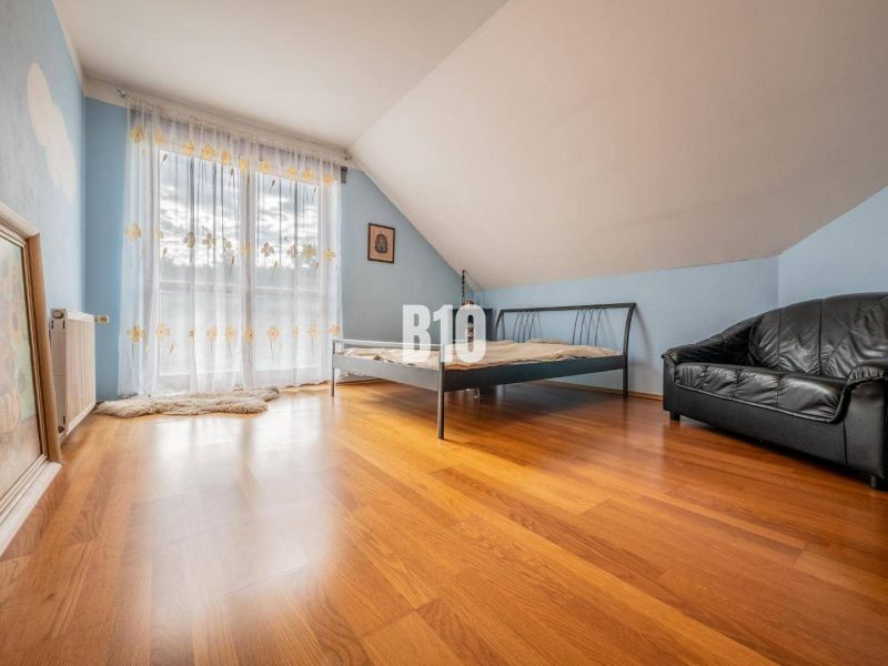Schlafzimmer im Einfamilienhaus mit Bett, Ledersofa und Holzboden.