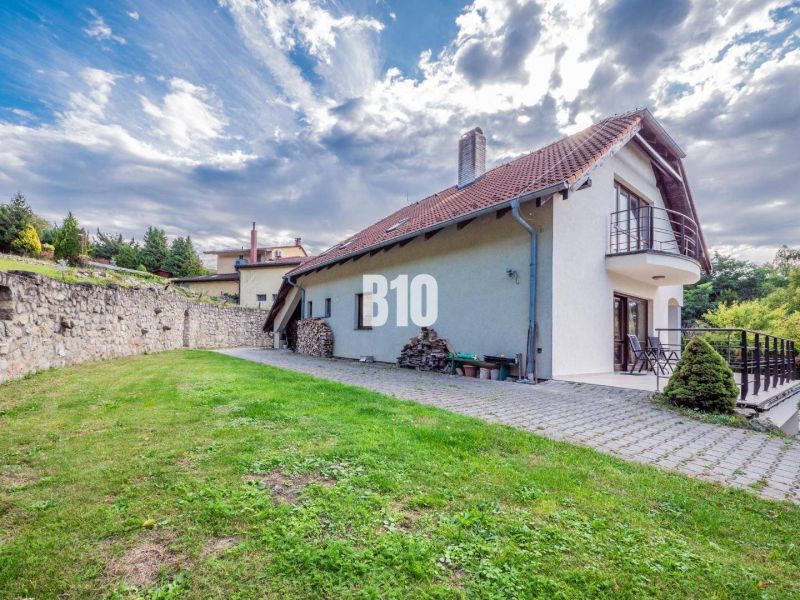 Ein Einfamilienhaus in Marianka, mit Terrasse und Rasen, umgeben von einer Steinmauer.