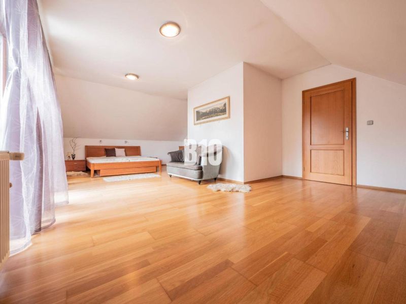 Ein geräumiges, helles Zimmer, Holzboden, Bett und Sessel, Einfamilienhaus.