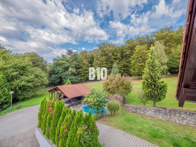 Garten mit Unterstand in Marianka bei einem Einfamilienhaus, umgeben von Bäumen und Rasen.