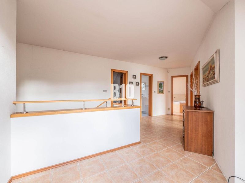 Flur mit Keramikfliesen, Holzgeländer und Schrank in einem Einfamilienhaus.