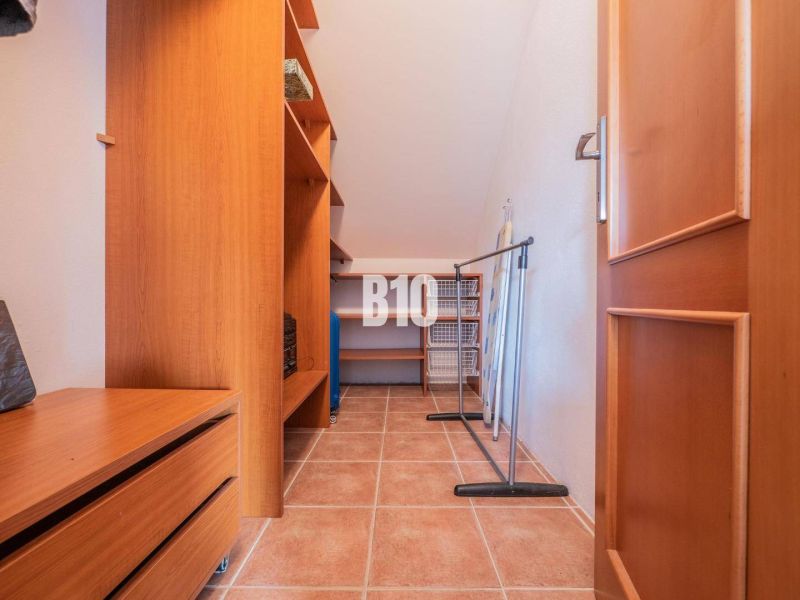 Ein Kleiderschrank in einem Einfamilienhaus mit Schränken, Regalen und Fliesenboden.