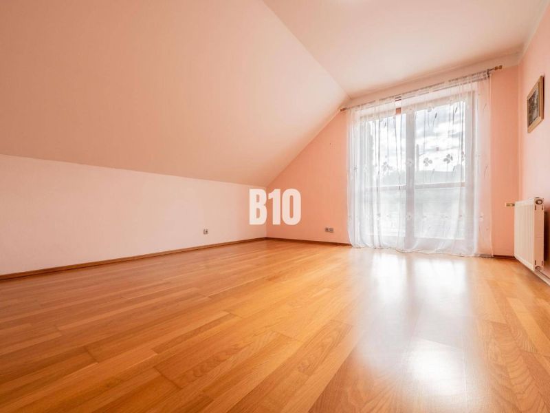 Ein geräumiges Zimmer mit Holzboden und einem französischen Fenster in einem Einfamilienhaus.
