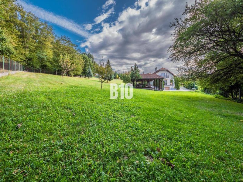 Ein Einfamilienhaus in Marianka mit Garten und Waldkulisse unter blauem Himmel.