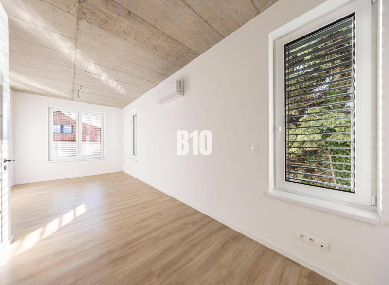 Ein Zimmer in einem Einfamilienhaus mit einem Boden in Holzoptik und weißen Wänden.