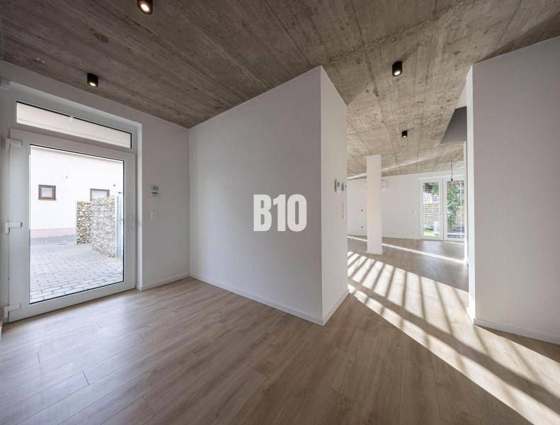 Innenraum eines Einfamilienhauses mit Betondecke und Boden in Holzoptik.