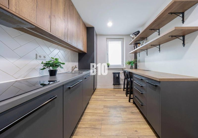 Küche in einer 3-Zimmer-Wohnung mit einem Boden in Holzoptik und einfachen Stauraumlösungen.