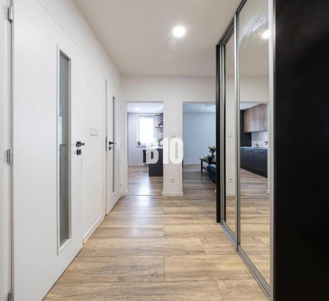 Ein Flur mit einem Boden in Holzoptik, weißen Türen und Einbauschränken in einer 3-Zimmer-Wohnung.