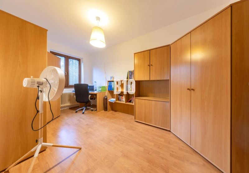 Ein Zimmer in einem Einfamilienhaus mit Holzmöbeln und einem Boden in Holzoptik.