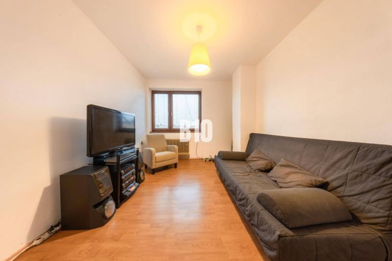 Wohnzimmer in einem Einfamilienhaus mit Sofa, Fernseher und Holzboden.