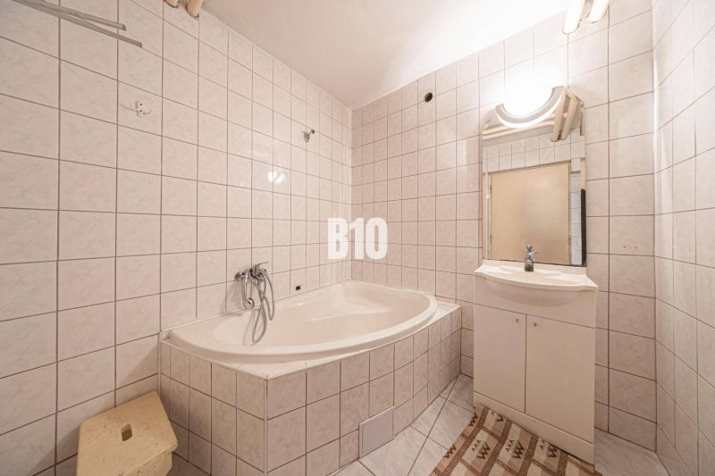 Ein Badezimmer mit Badewanne und Waschbecken in einem Einfamilienhaus, gefliest mit hellen Fliesen.