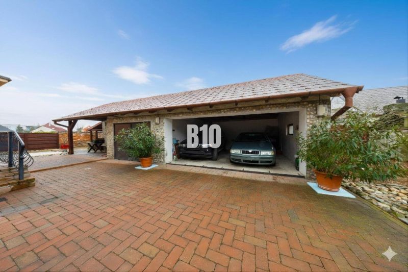 Ein Einfamilienhaus in Štvrtok na Ostrove mit einer Garage für zwei Autos und einem gepflasterten Hof.
