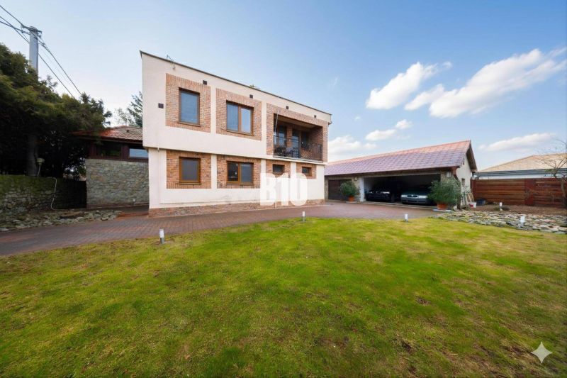 Ein Einfamilienhaus in Štvrtok na Ostrove mit Garage, Rasenfläche und Ziegelfassadendekor.
