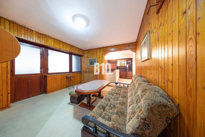 Wohnzimmer eines Einfamilienhauses mit Holzverkleidung und bequemer Couch.
