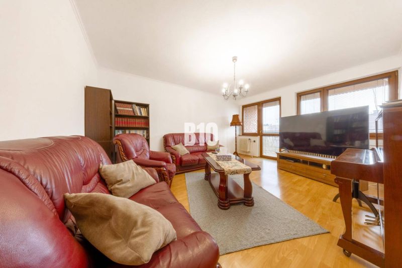 Wohnzimmer in einem Einfamilienhaus mit Ledersofa, Bücherregal und Holzboden.